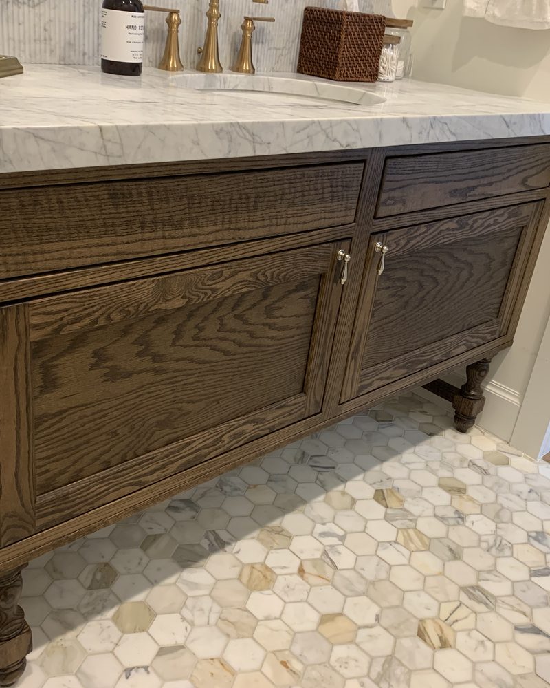 Close view of a carved wood vanity with drawers and sinks