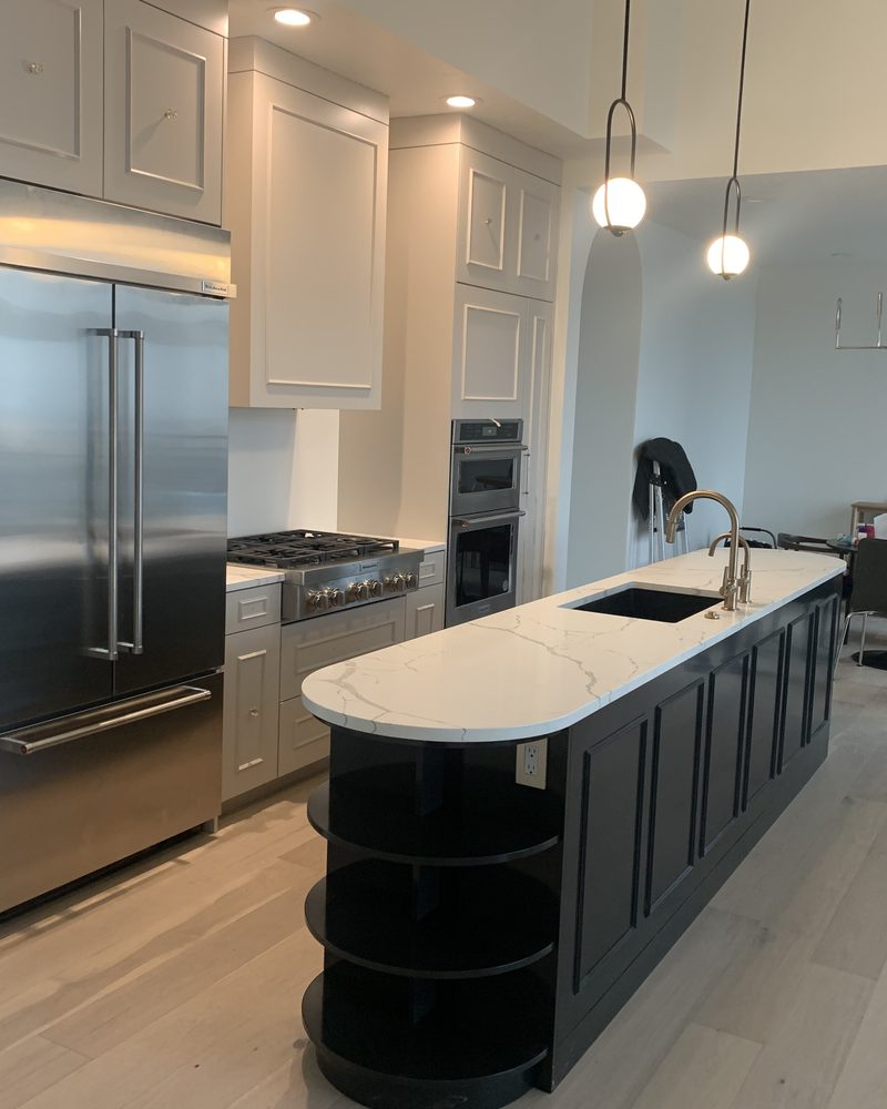 White kitchen with a dark island and full-height cabinetry
