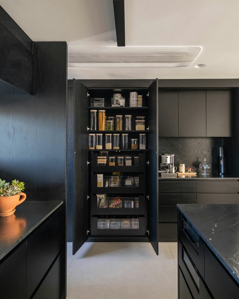 Open black pantry cabinet with organized shelves and pull-out storage